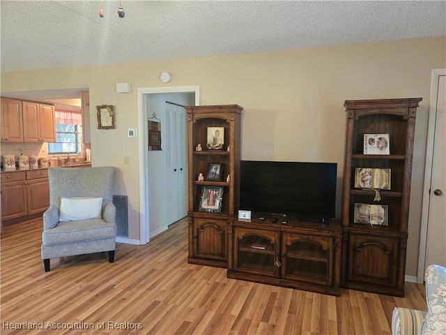 living room featuring light wood-style floors, a textured ceiling, and visible vents