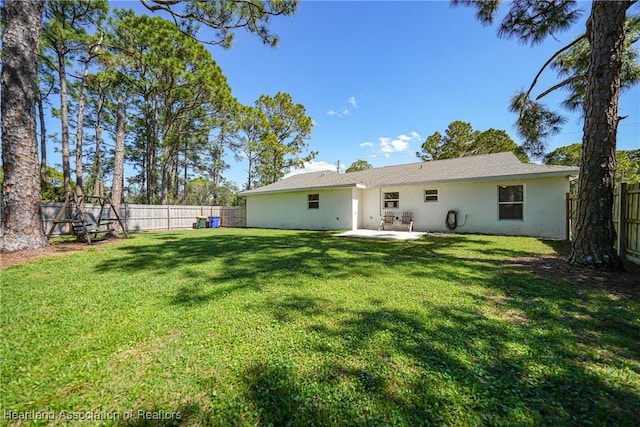 rear view of property with stucco siding, a fenced backyard, a patio, and a yard