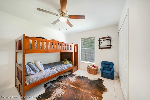 tiled bedroom with ceiling fan and baseboards