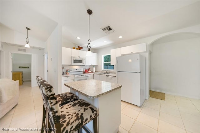 kitchen with lofted ceiling, white appliances, visible vents, and a center island