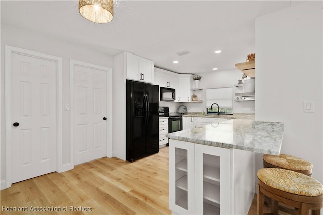 245 Lake Blvd, Sebring, FL 33875 - kitchen featuring black appliances, open shelves, a peninsula, white cabinets, and light stone counters