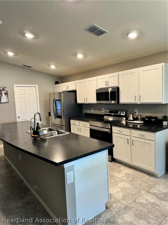 kitchen with appliances with stainless steel finishes, a center island with sink, white cabinetry, and sink