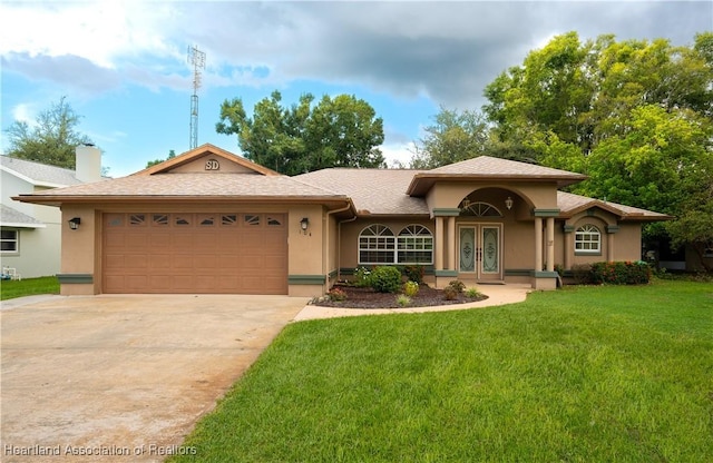 view of front of home featuring a front yard, driveway, stucco siding, french doors, and a garage