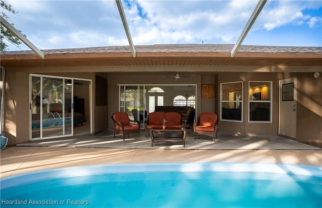 back of house featuring ceiling fan, stucco siding, glass enclosure, an outdoor pool, and a patio