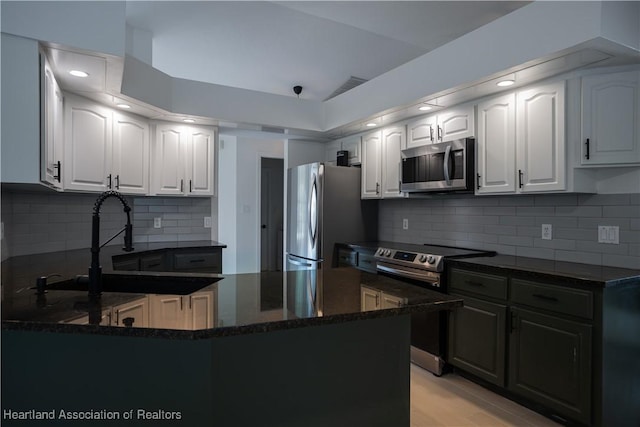 kitchen featuring white cabinetry, dark stone counters, a peninsula, and stainless steel appliances