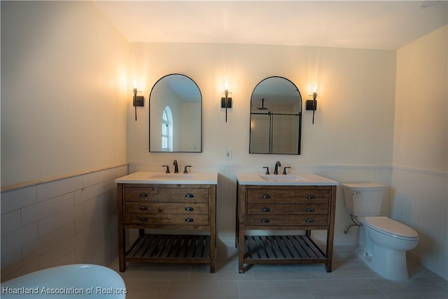 bathroom featuring vanity, toilet, tile patterned flooring, and wainscoting
