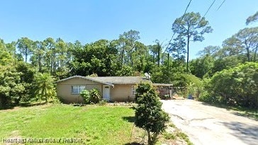 view of side of home featuring driveway and a lawn