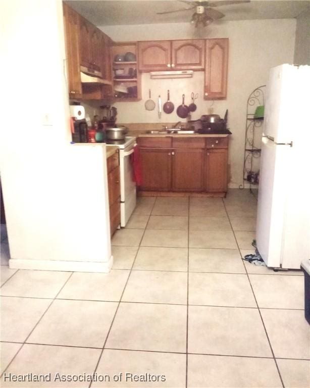 kitchen featuring a sink, light tile patterned flooring, white appliances, ceiling fan, and under cabinet range hood