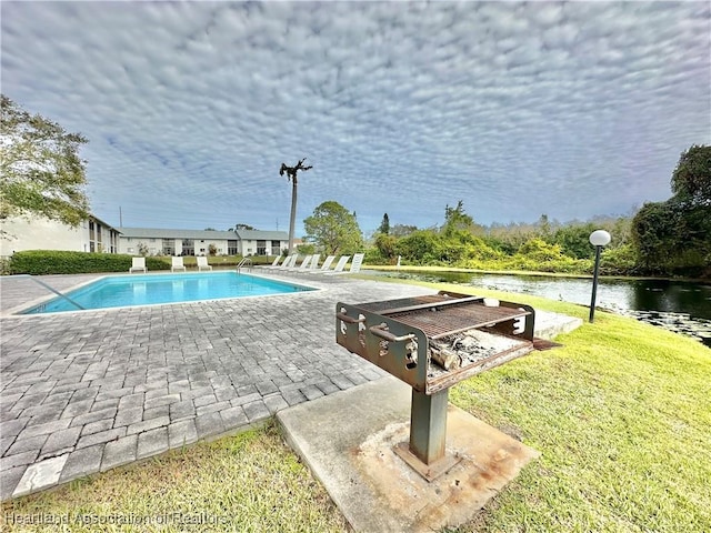 view of pool featuring a patio, a yard, and a water view