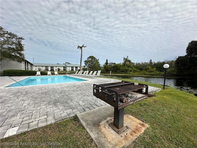 view of swimming pool with a yard and a water view