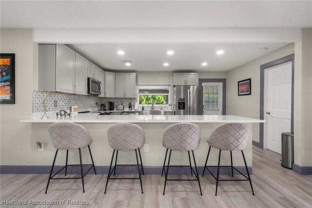 1622 Dinner Dr, Sebring, FL 33870 - kitchen with a kitchen bar, backsplash, appliances with stainless steel finishes, a peninsula, and light countertops