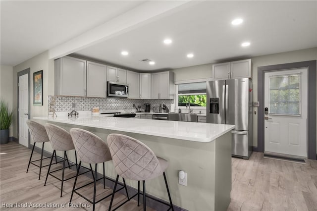 1622 Dinner Dr, Sebring, FL 33870 - kitchen featuring decorative backsplash, a peninsula, stainless steel appliances, and light wood-style floors