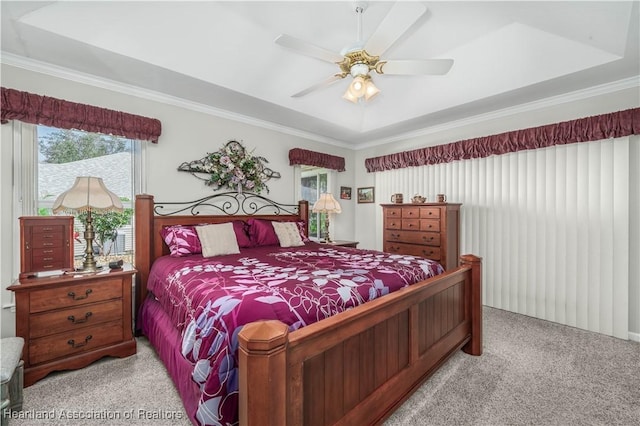 bedroom with a raised ceiling, ceiling fan, light carpet, and ornamental molding