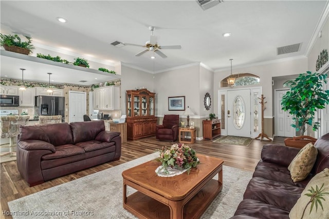 living room featuring wood-type flooring, ceiling fan, and ornamental molding