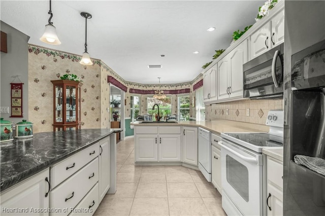 kitchen with white cabinetry, tasteful backsplash, pendant lighting, light tile patterned floors, and appliances with stainless steel finishes