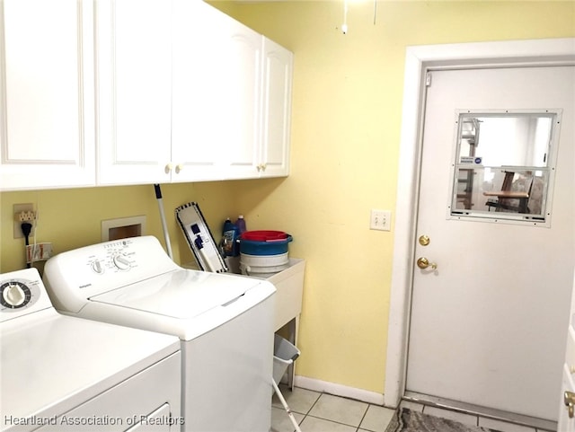 washroom featuring light tile patterned floors, washing machine and dryer, cabinet space, and baseboards