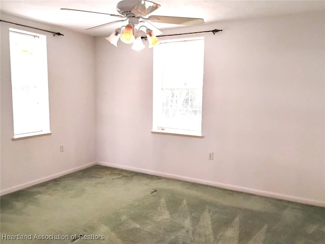 carpeted spare room featuring ceiling fan and baseboards