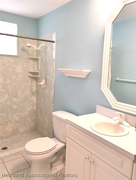 bathroom featuring toilet, tile patterned floors, a walk in shower, and vanity