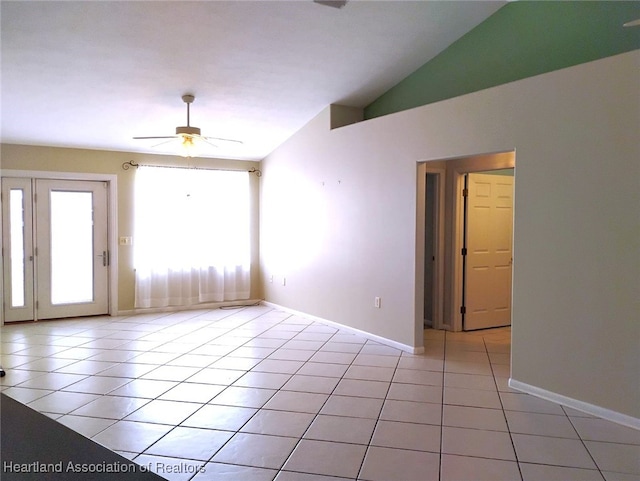 unfurnished room with ceiling fan, vaulted ceiling, baseboards, and light tile patterned floors