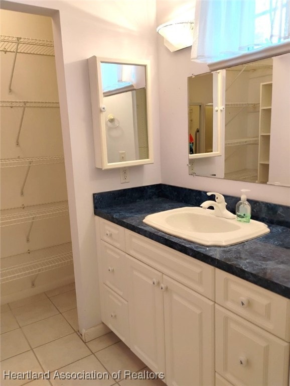 full bathroom featuring tile patterned flooring, a walk in closet, and vanity