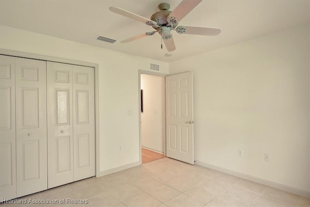 unfurnished bedroom with light tile patterned floors, a closet, visible vents, and baseboards