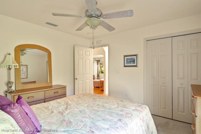 bedroom with ceiling fan, a closet, visible vents, and light colored carpet