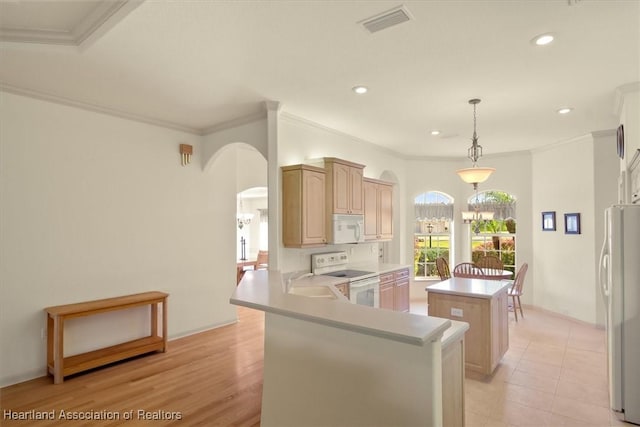 kitchen featuring arched walkways, a notable chandelier, white appliances, a sink, and a center island