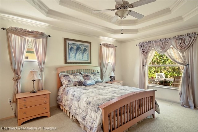 bedroom featuring a tray ceiling, light colored carpet, and crown molding