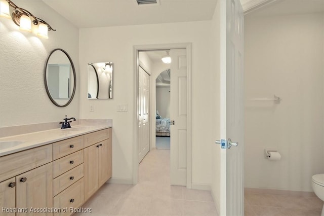 ensuite bathroom featuring connected bathroom, tile patterned flooring, a sink, and double vanity