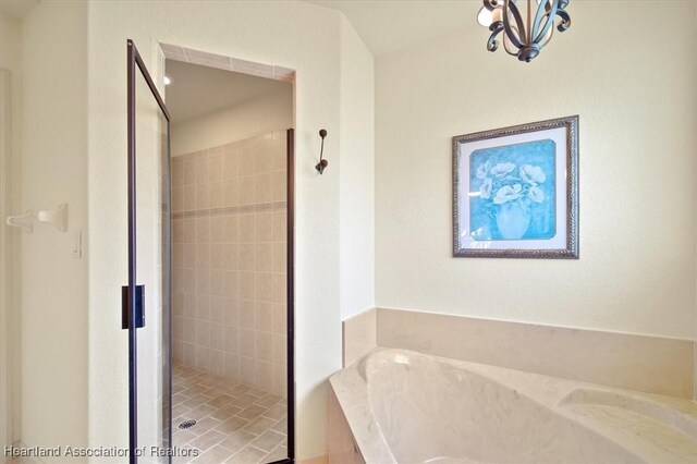 bathroom with a shower stall, a chandelier, and a bath