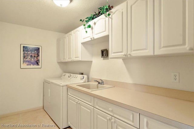 laundry room with cabinet space, light tile patterned floors, baseboards, independent washer and dryer, and a sink