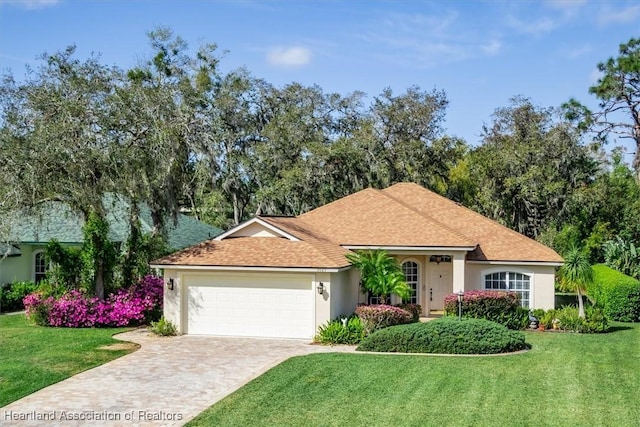 view of front of home with an attached garage, decorative driveway, a front yard, and stucco siding