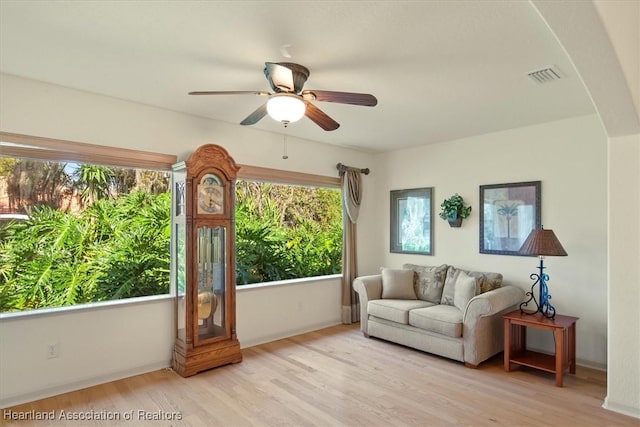 sitting room featuring light wood-type flooring, visible vents, and a ceiling fan