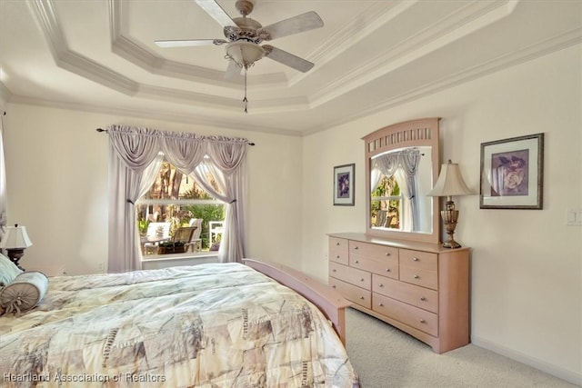 carpeted bedroom with a tray ceiling, multiple windows, and crown molding