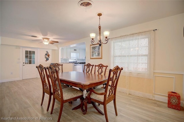 dining space with light hardwood / wood-style flooring and ceiling fan with notable chandelier