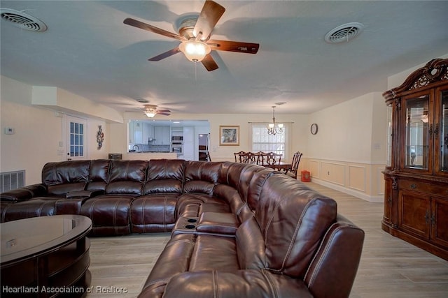 living room featuring light hardwood / wood-style floors and ceiling fan with notable chandelier