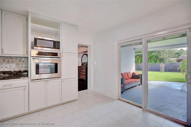 kitchen with backsplash, light tile patterned flooring, white cabinets, and stainless steel appliances