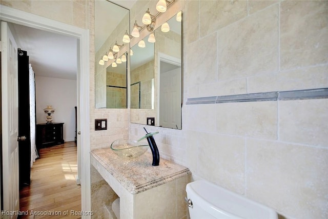 bathroom featuring hardwood / wood-style flooring, toilet, and tile walls