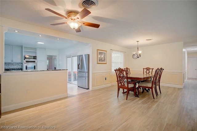 dining area featuring ceiling fan with notable chandelier and light wood-type flooring