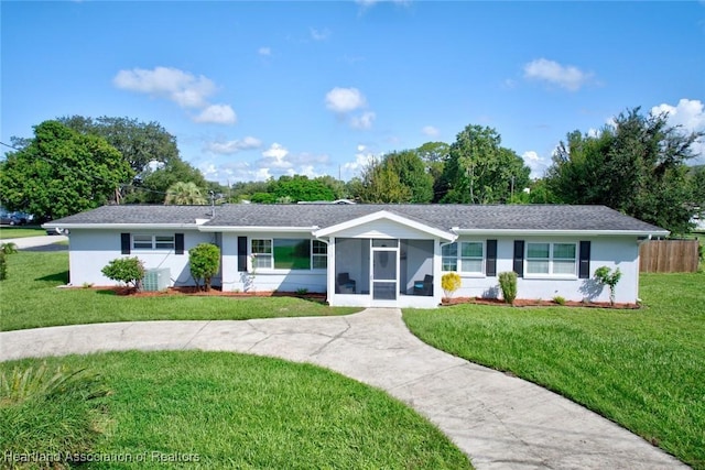 ranch-style house with a front lawn, cooling unit, and a sunroom