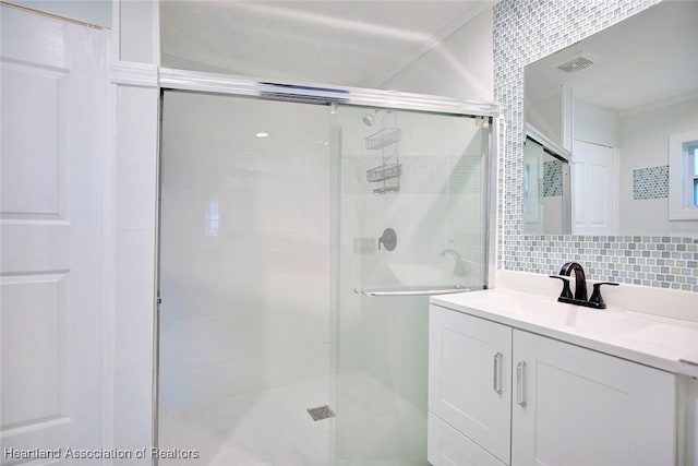 bathroom with vanity, a shower with door, and tasteful backsplash