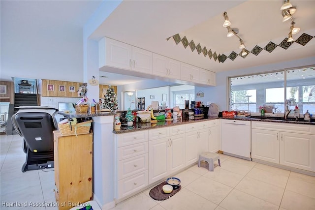 kitchen featuring sink, light tile patterned floors, white dishwasher, white cabinets, and kitchen peninsula