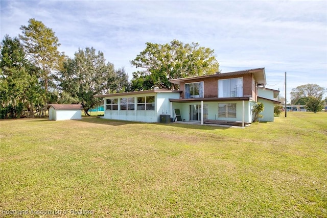 back of property with a yard, central air condition unit, and a storage unit