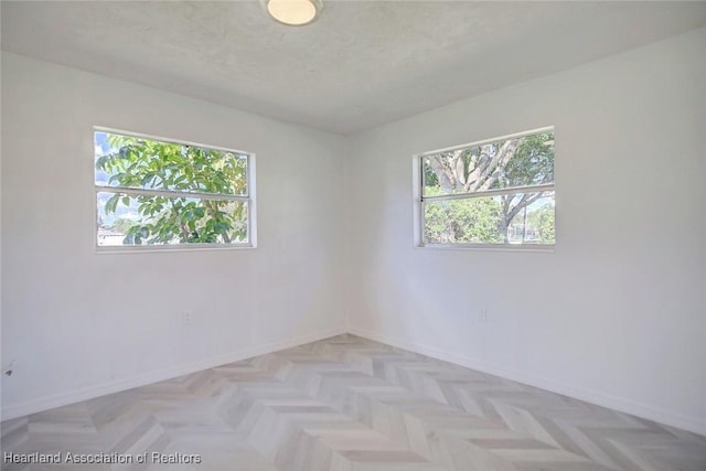 empty room with a wealth of natural light, light parquet flooring, and a textured ceiling