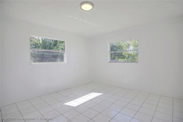 tiled spare room with wooden walls and a healthy amount of sunlight