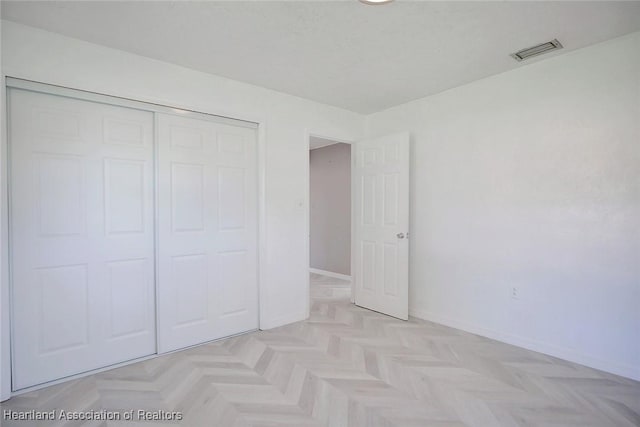 unfurnished bedroom with light parquet flooring and a closet