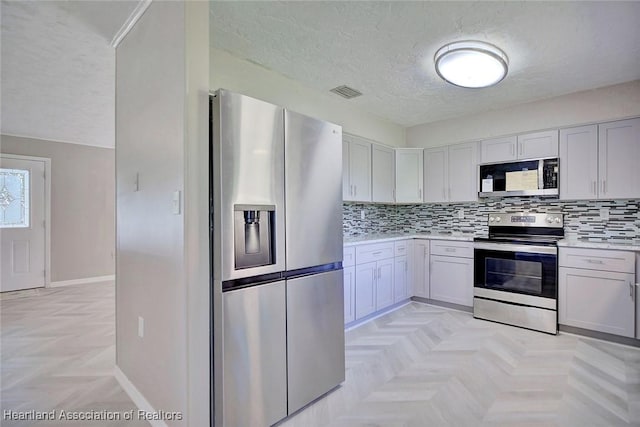 kitchen featuring tasteful backsplash, light parquet flooring, and appliances with stainless steel finishes