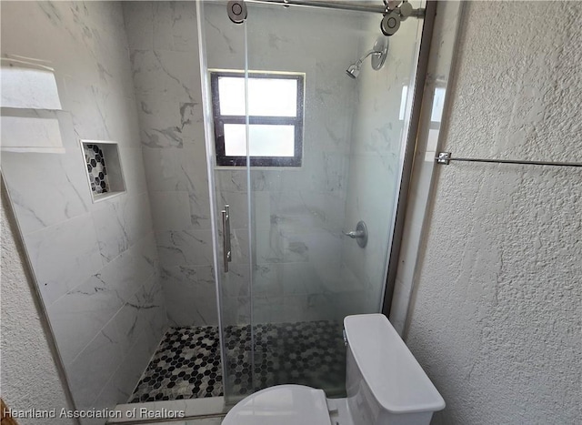 bathroom featuring toilet and a shower with shower door