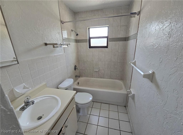 full bathroom featuring tiled shower / bath combo, tile patterned flooring, toilet, vanity, and tile walls