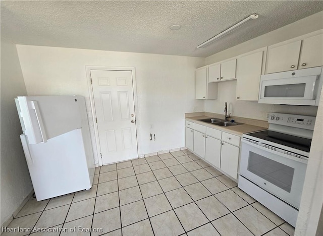 kitchen with white appliances, white cabinets, sink, light tile patterned floors, and a textured ceiling